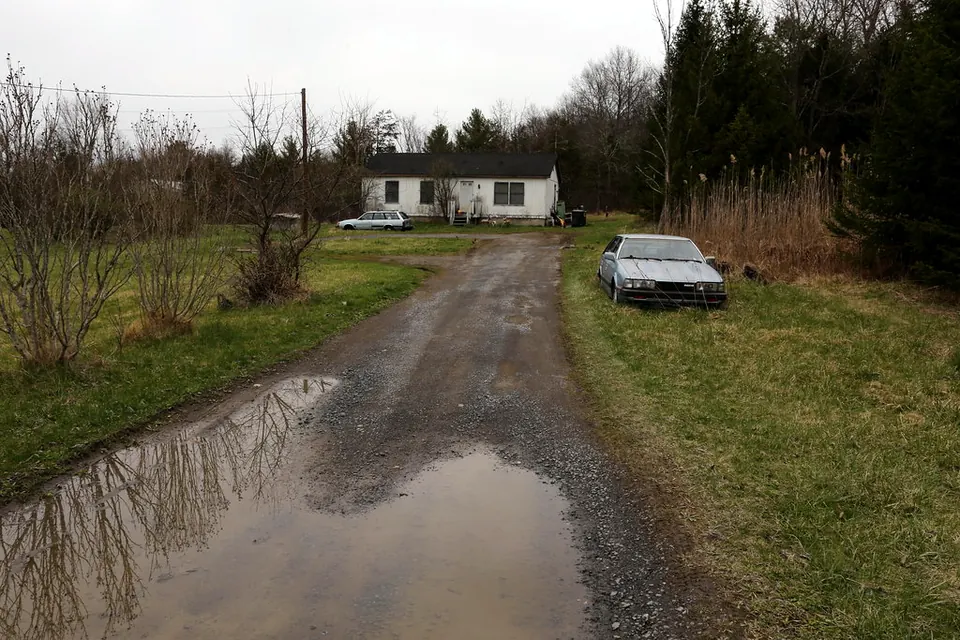 Standing water pooled across a residential driveway after rain, house in the background