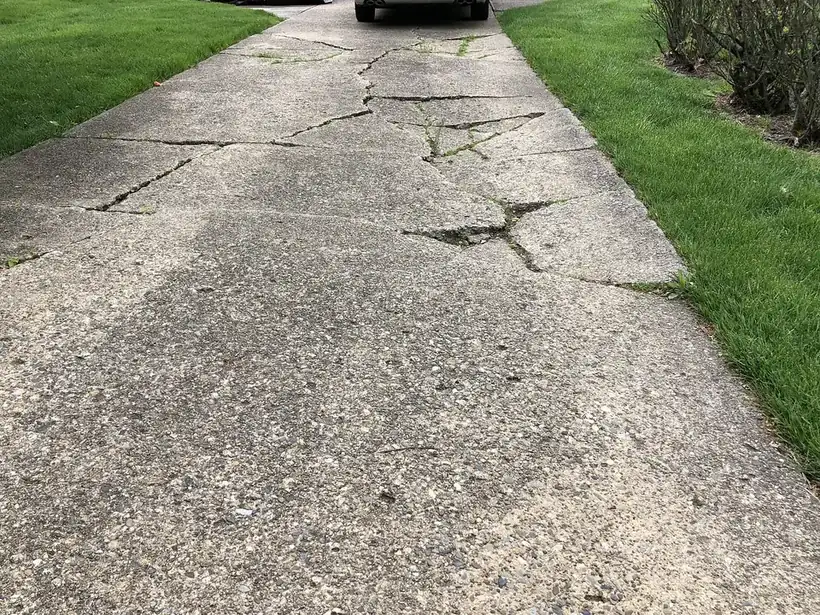 Old concrete driveway with widespread cracking and buckling